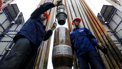 Workers secure drilling pipe sections on an oil drilling tower operated by Tatneft near Almetyevsk, Russia. Crude oil prices are near four-year lows and are only expected to fall further as a price war between Russia and Saudi Arabia floods global markets