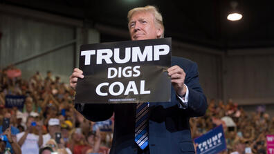 U.S. President Donald Trump holds up a "Trump Digs Coal" sign at a rally in West Virginia, one of the states hit by the coal industry's sharp decline, on Aug. 3, 2017.