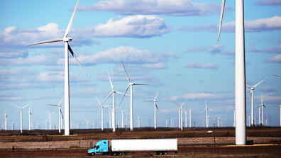 a truck drives past wind turbines