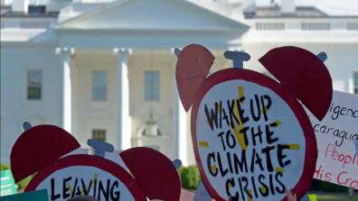 protesters in front of the white house hold signs reading "wake up to the climate crisis"